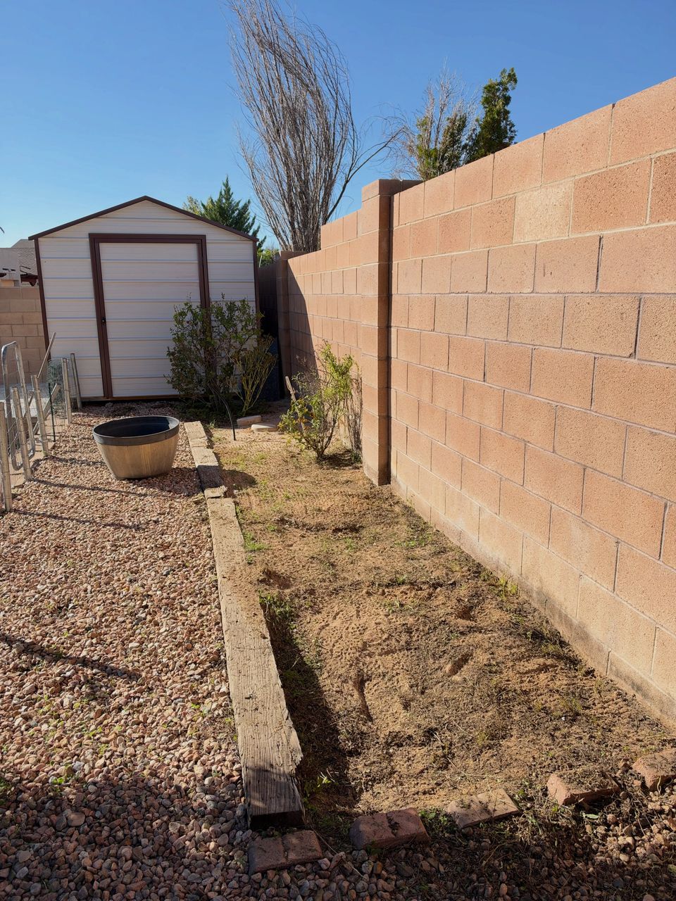 The same side yard after: weeds pulled from the planter bed and the gravel cleared along the block wall.